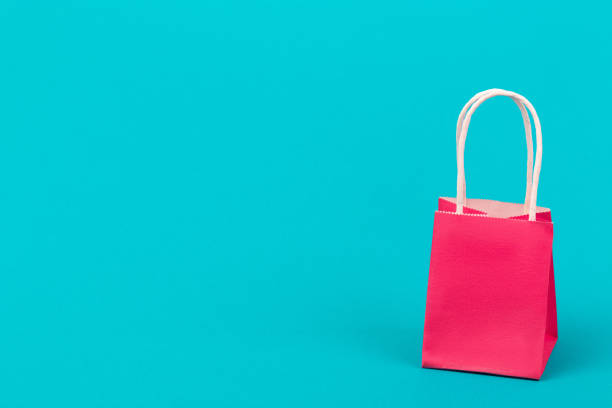 istock Paper gift pink bag package close-up on blue background with copy space. 1291532866