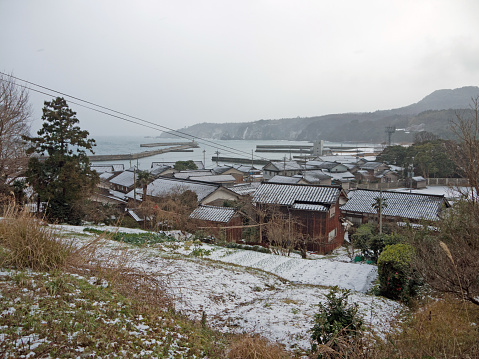 Small japanese Noroshimachi coastal village and harbor winter view, traditional houses and filed in snowfall, Noto peninsula, Japan