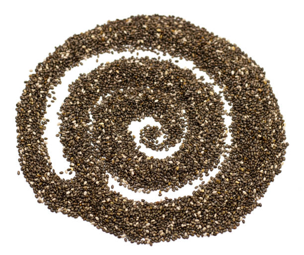 白い背景に分離された抽象的なスパイラルの形で暗いチア種子。スペインセージの小粒 - tablespoon chia healthy eating seed ストックフォトと画像