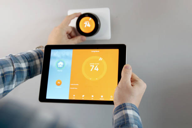 istock Man is Adjusting a temperature using a tablet with smart home app in modern living room 1291537105
