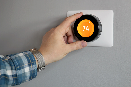 Woman Setting Temperature On Air Conditioner Control Panel In Hotel Room