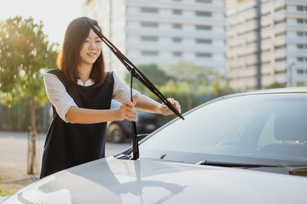 Young asian woman checking windshield wiper Image of an Asian Chinese woman check her windshield wiper before the journey windshield wiper stock pictures, royalty-free photos & images