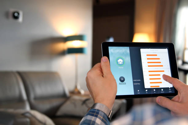 Man is Adjusting a temperature using a tablet with smart home app in modern living room stock photo