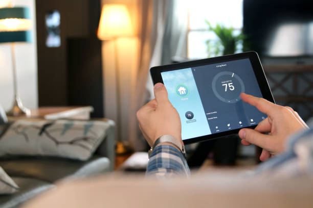 istock Man is Adjusting a temperature using a tablet with smart home app in modern living room 1291538216