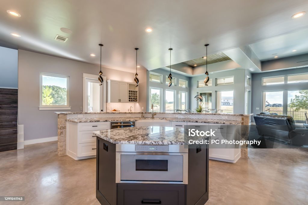 A smaller island inside of a larger L-shaped island in new kitchen Vinyl flooring throughout open concept floor plan Kitchen Island Stock Photo