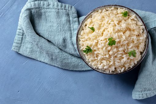Rice in a bowl, overhead shot on a blue background with copyspace