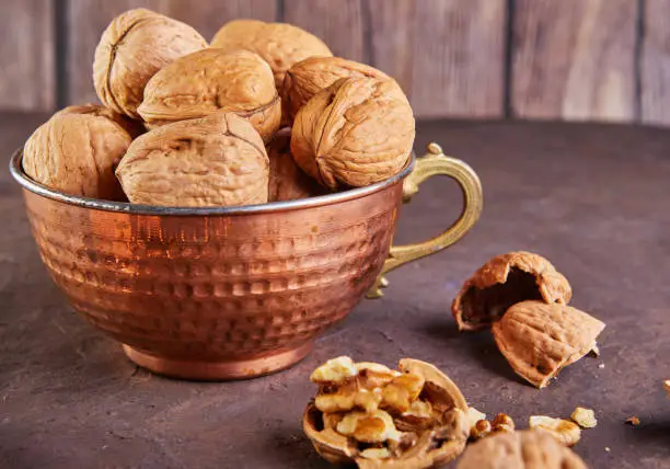 Photo of Walnuts in a tin cup, whole and finely chopped, next to the filling and shell. Home storage of winter preparations