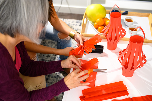 Mother and adult daughter making lanterns for Chinese New Years. Traditional Chinese New Years at home. Modern Chinese culture.