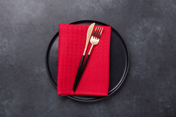 istock Table setting with black ceramic plate and cutlery on black stone background. Top view. Copy space 1291544611
