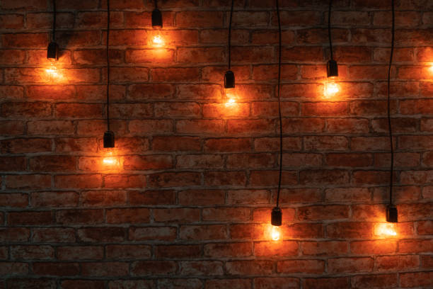 istock Some lightbulbs are hanging over a brick wall. 1291548000