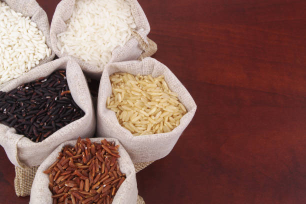 Different kinds of rice in burlap sacks - white, brown, red and black rice.