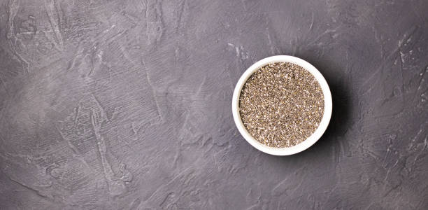 黒い石の背景に白いボウルに暗いチアの種。スペインセージの小粒 - tablespoon chia healthy eating seed ストックフォトと画像