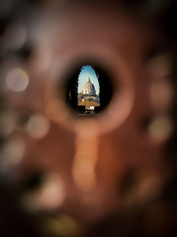 A singular view of the dome of St. Peter's Basilica through the door lock outside the garden of the Priory of the Order of the Knights of Malta, on the Aventine hill, in the heart of the Eternal City.