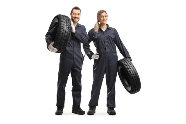 Male and female auto mechanic workers carrying car tires isolated on white background