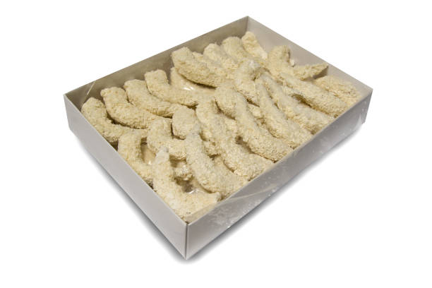 istock Processing of crispy breaded shrimps in a standard factory box isolated on a white background. Breaded raw shrimps. Side view 1291554076