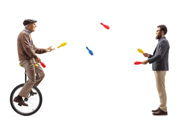 istock Younger and elderly manon a unicycle juggling 1291556212