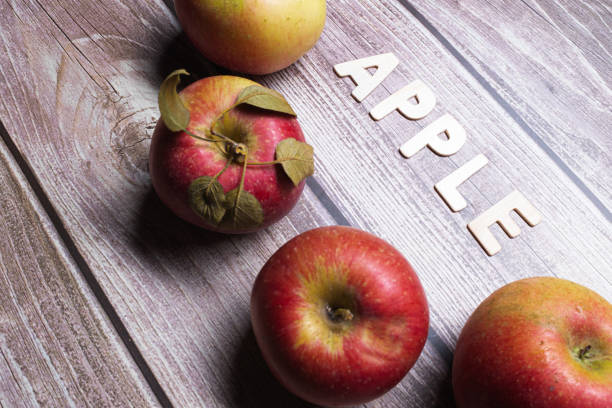 istock Red apples fruit on a wooden table with word apple on a diagonal position 1291561041