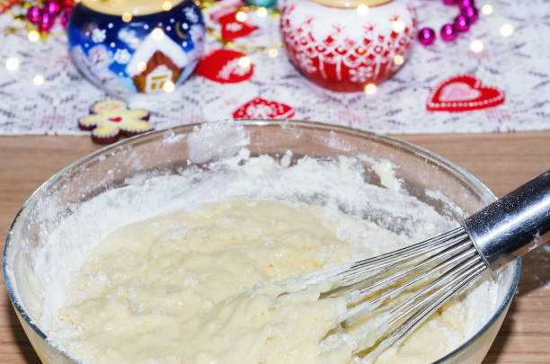 Kneading cookie dough on the background of Christmas decorations, whisk close-up. Selective focus