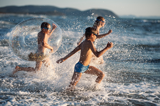 Brothers and sister are having fun on the beach. Kids are running on the beach into the sea
Nikon D850
