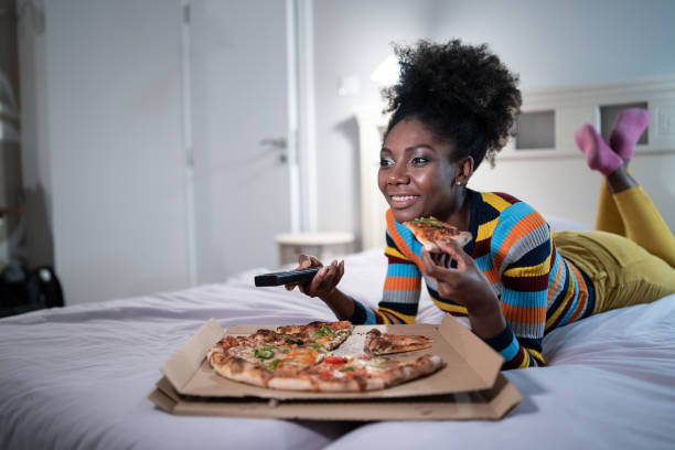 istock Single woman eating pizza and watching tv 1291567055