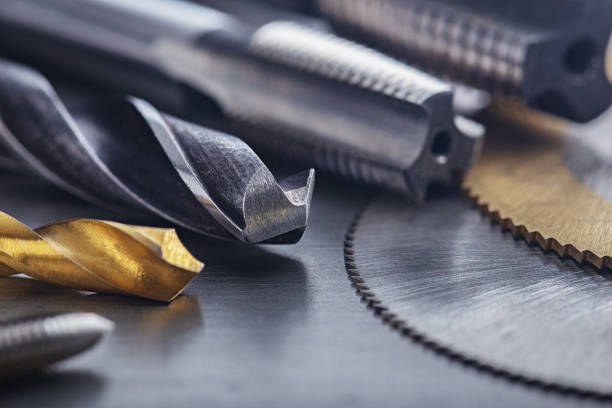 set of different drill bits,thread tap and mill cutters on steel plate background. Locksmithing deal.