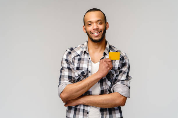 istock Young african-american man smiling and showing credit card with empty copy space 1291570610