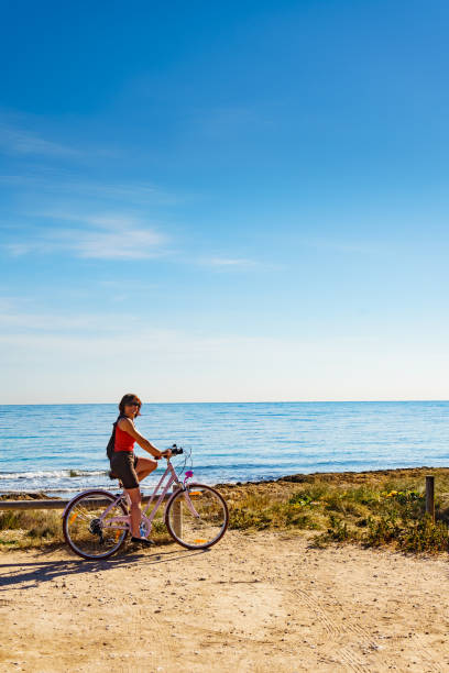 istock Woman ride bicycle on beach, active lifestyle. 1291570814