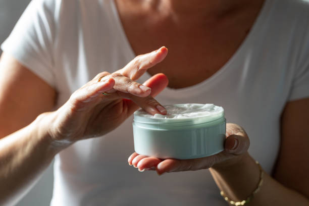 istock Picking white face cream with finger from jar for application 1291572115