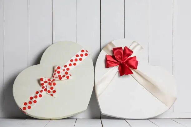 Two Heart shape boxes with red ribbons and bows on white wooden background, Valentine day gifts