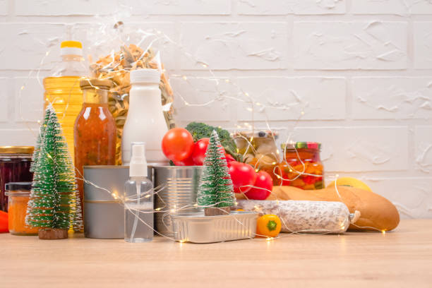 istock Christmas donations - food donations on light background with copyspace - pasta, fresh vegatables, canned food, baguette, cooking oil with Christmas decorations. Food bank. Selective focus 1291573507