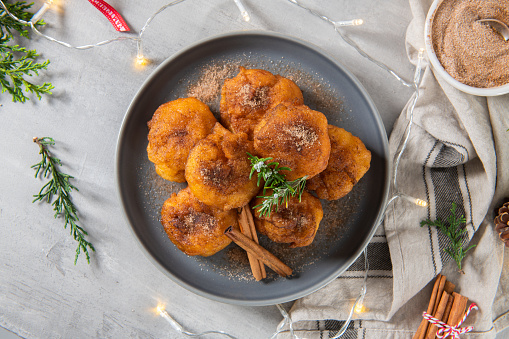 Traditional portuguese Christmas sweets Sonhos with sugar and cinnamon on kitchen countertop.