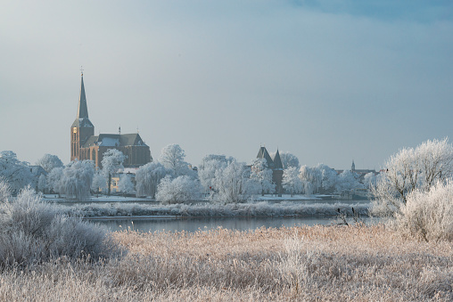 View on Kampen and river IJssel in winter in Holland. Kampen is an ancient Hanseatic League in Overijssel, The Netherlands. The Bovenkerk is visible in the foreground of the city.