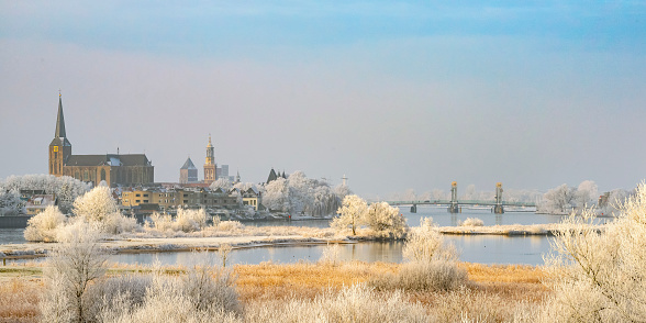 View on Kampen and river IJssel in winter in Holland. Kampen is an ancient Hanseatic League in Overijssel, The Netherlands. The Bovenkerk is visible in the foreground of the city.