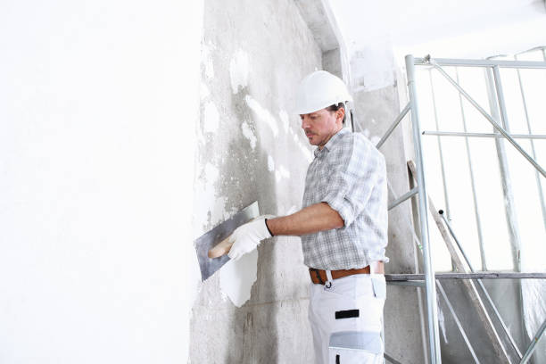 istock plasterer man at work with trowel plastering the wall of interior construction site wear helmet and protective gloves, scaffolding on background and copy space on white wall 1291578413