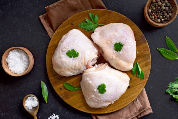 muslo de pollo crudo en tabla de cortar de madera - chicken thighs fotografías e imágenes de stock