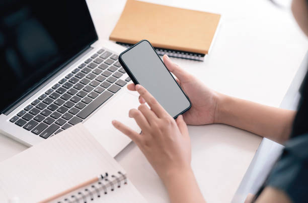 istock Cropped shot of female hands using smartphone while sitting at her office desk. 1291584593