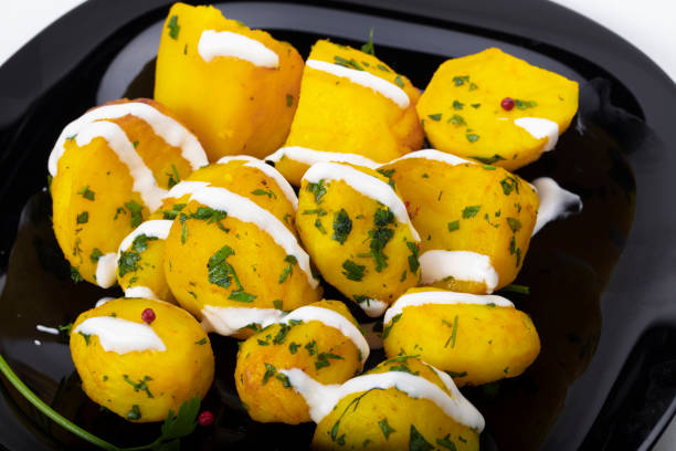 Baked potatoes sprinkled with herbs on a black plate.