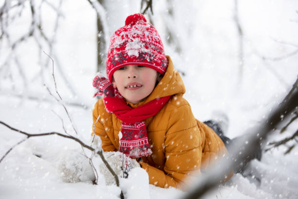 istock A happy boy in warm clothes lies in a snowdrift. 1291586087