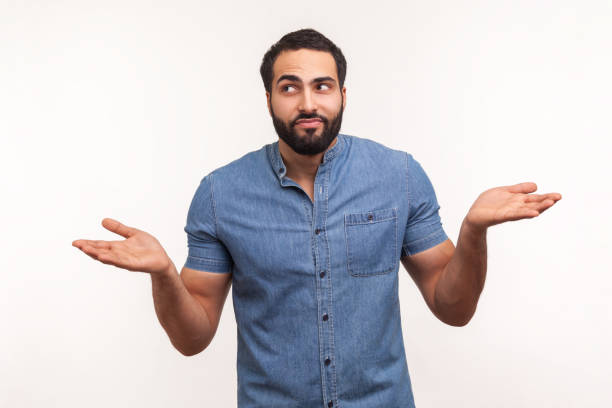 istock Puzzled clueless man with beard in blue shirt throwing up his hands looking at camera with uncertain expression, has no answers 1291589147