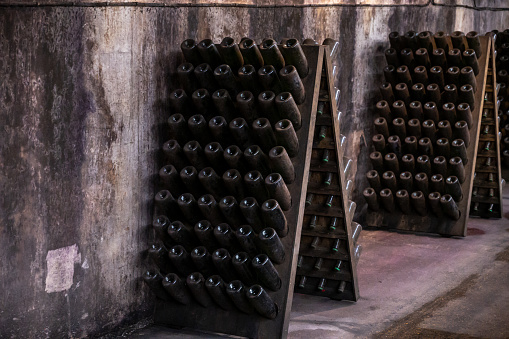 Champagne sparkling wine production in bottles in racks in dark underground cellar, Reims, Champagne, France