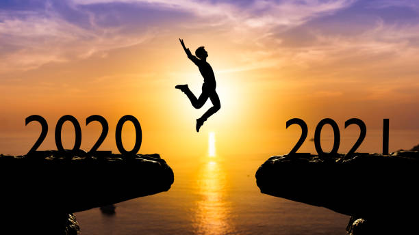 istock Silhouette man jump between 2020 and 2021 years with sunset background,year 2021 concept 1291591420