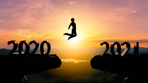 istock Silhouette man jump between 2020 and 2021 years with sunset background,year 2021 concept 1291591421