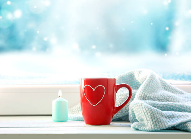 Red mug on window sill empty copy space,valentine's day background,winter card mood concept.Cozy christmas time.