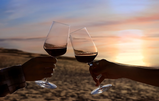 Selective focus of couple hands which  Couple drinking wine in sea restaurant on the beach background