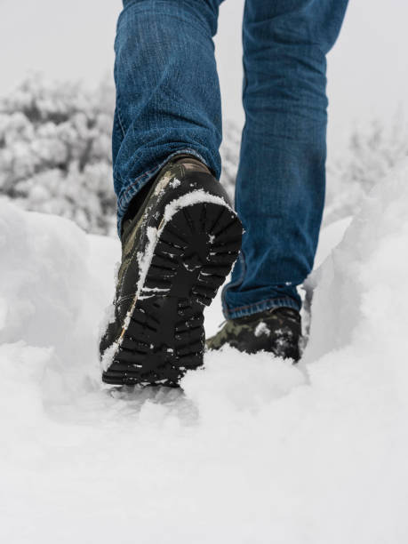 istock Man with jeans trekking on snowy path 1291592601