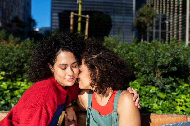 istock Smiling lesbian couple embracing and relaxing on a park bench 1291594432