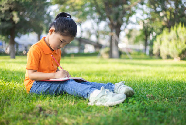 istock Cute little girl learning on the lawn 1291596438