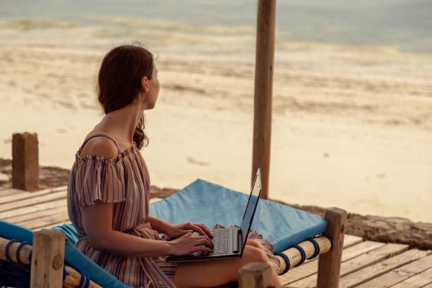 digitaler nomade arbeitet am laptop, während er am strand ist - facial expression isolated lifestyles exoticism stock-fotos und bilder
