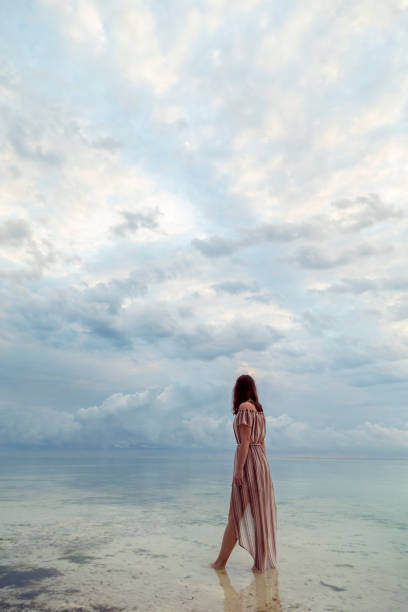 istock Woman walking down the beach in dawn 1291603078