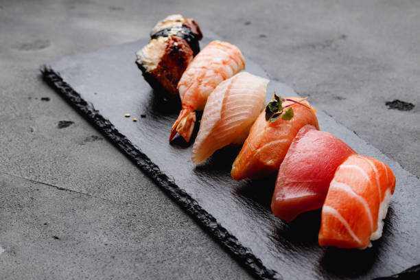 set de nigiri sushi servido en plato sobre fondo gris - nigiri fotografías e imágenes de stock